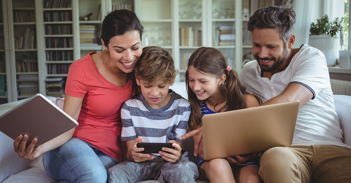 principais duvidas sobre roteadores - familia reunida no sofa vendos celulares e tablets