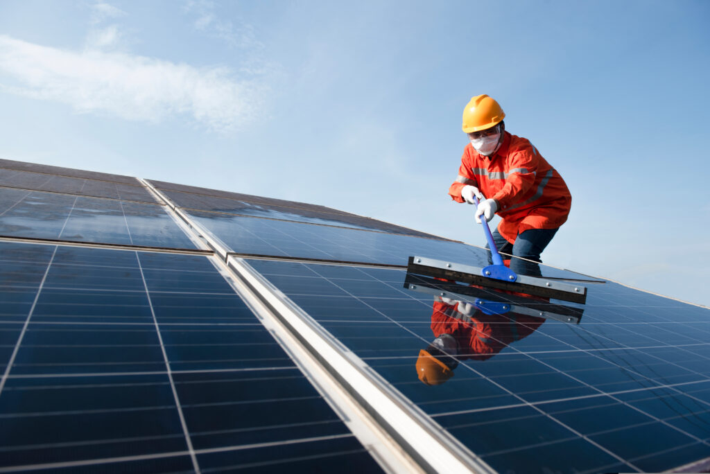 profissional eletricistas realizando a limpeza de placas de geração de energia fotovoltaica